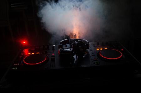 DJ Spinning, Mixing, and Scratching in a Night Club, Hands of dj tweak various track controls on dj's deck, strobe lights and fog, selective focus, close upの写真素材