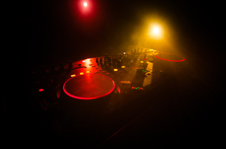 DJ Spinning, Mixing, and Scratching in a Night Club, Hands of dj tweak various track controls on dj's deck, strobe lights and fog, selective focus, close upの写真素材