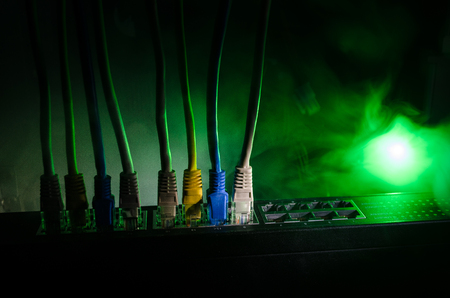 Network switch and ethernet cables, symbol of global communications. Colored network cables on dark background with lights and smoke. Selective focus. Network internet concept backgroundの写真素材