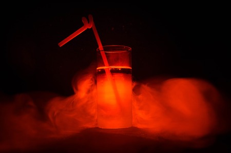Glass of Red Alcoholic Cocktail on Dark Background with smoke and backlight. Fire hot coctailの写真素材