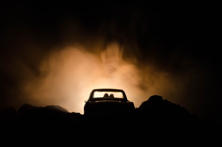 silhouette of car with couple inside on dark background with lights and smoke. Romantic scene