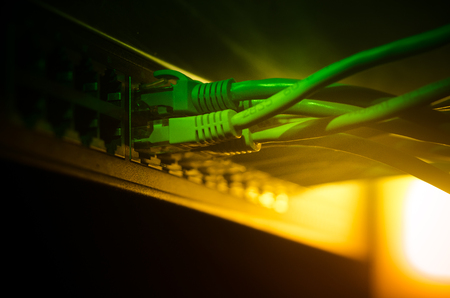 Network switch and ethernet cables, symbol of global communications. Colored network cables on dark background with lights and smoke. Selective focus. Network internet concept backgroundの写真素材