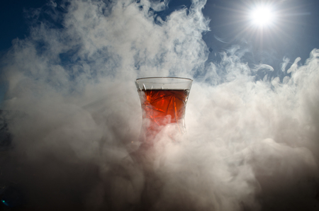 Turkish Azerbaijan tea in traditional glasse and pot outdoor nature background with sunlight and smoke. Eastern tea concept. Armudu traditional cup. Sunset timeの写真素材