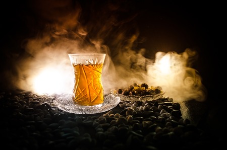 Turkish Azerbaijan tea in traditional glasse and pot on black background with lights and smoke. Eastern tea concept. Armudu traditional cupの写真素材