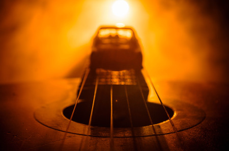 Music concept. Acoustic guitar isolated on a dark background under beam of light with smoke with copy space. Guitar Strings, close up. Selective focus. Fire effects. Surreal guitarの写真素材