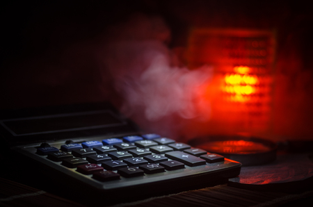 Business accessories (magnifier, calculator and brushes) and graphics, tables, charts on a table with dark background. Selective focus.の写真素材
