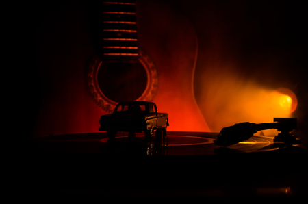 Vintage vinyl record playing on player and acoustic guitar on background with fire orange smoke. Blues concept. With Toy carの写真素材