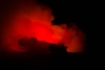 Burning car on a dark background. Car catching fire, after act of vandalism or road indicent. Burning vintage car nightshotの写真素材