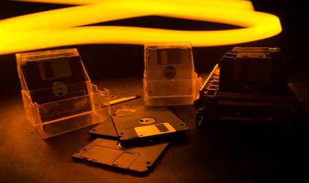 Pile of black floppy disks (diskette) on dark background with lightの写真素材