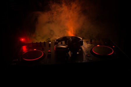 DJ Spinning, Mixing, and Scratching in a Night Club, Hands of dj tweak various track controls on dj's deck, strobe lights and fog, selective focus, close upの写真素材