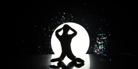 Conceptual image with sandglass and and man with moon at background with fog. Silhouette of toy figure touching hourglass. deadline concept. Man rising handsの写真素材
