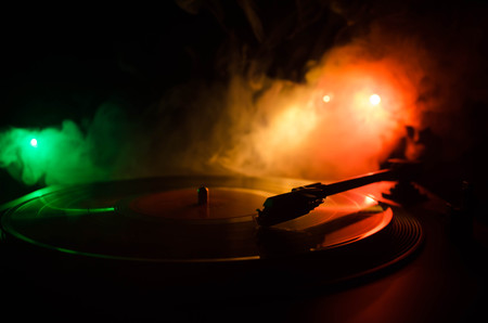 Turntable vinyl record player. Retro audio equipment for disc jockey. Sound technology for DJ to mix & play music. Vinyl record being played against burning fire background with smokeの写真素材