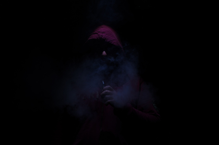 Vaping man holding a mod. A cloud of vapor. Black background. Vaping an electronic cigarette with a lot of smoke. Vape conceptの写真素材