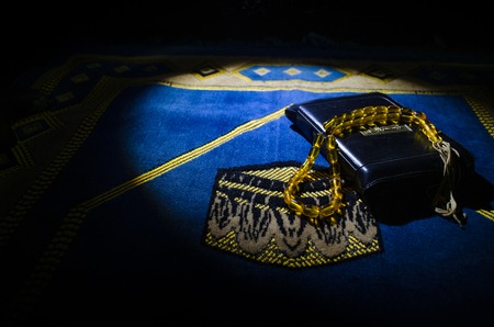 Holy Quran with beads on a prayer mat, Muslim Tasbih is a string of prayer beads which is traditionally used by Muslims along with the Quran. Ramadan holidays concept. Selective focusの写真素材