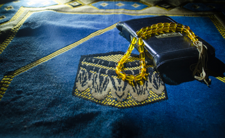 Holy Quran with beads on a prayer mat, Muslim Tasbih is a string of prayer beads which is traditionally used by Muslims along with the Quran. Ramadan holidays concept. Selective focusの写真素材