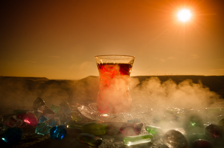 Turkish Azerbaijan tea in traditional glasse and pot outdoor nature background with sunlight and smoke. Eastern tea concept. Armudu traditional cup. Sunset timeの写真素材