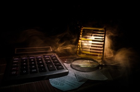Business accessories (magnifier, calculator and brushes) and graphics, tables, charts on a table with dark background. Selective focus.の写真素材