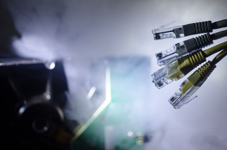 Network switch and ethernet cables, symbol of global communications. Colored network cables on dark background with lights and smoke. Selective focus. Network internet concept backgroundの写真素材