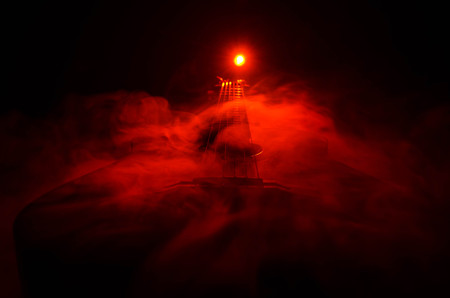 Music concept. Acoustic guitar isolated on a dark background under beam of light with smoke with copy space. Guitar Strings, close up. Selective focus. Fire effects. Surreal guitarの写真素材