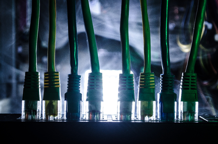 Network switch and ethernet cables, symbol of global communications. Colored network cables on dark...