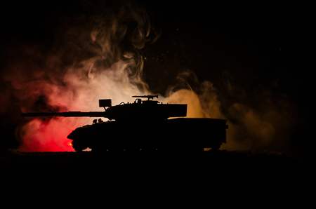 War Concept. Military silhouettes fighting scene on war fog sky background, German tank in action Below Cloudy Skyline At night. Attack scene. Armored vehicles. Tanks battle.の写真素材