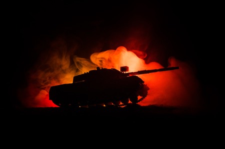 War Concept. Military silhouettes fighting scene on war fog sky background, German tank in action Below Cloudy Skyline At night. Attack scene. Armored vehicles. Tanks battle.の写真素材