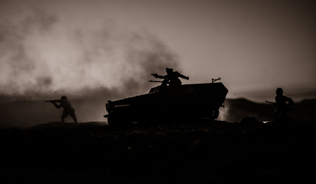War Concept. Military silhouettes fighting scene on war fog sky background, World War Soldiers Silhouettes Below Cloudy Skyline at sunset. Attack scene. Armored vehicles. German tank in actionの写真素材