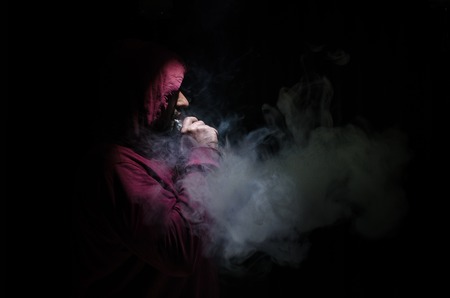 Vaping man holding a mod. A cloud of vapor. Black background. Vaping an electronic cigarette with a lot of smoke. Vape conceptの写真素材