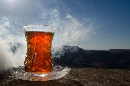 Turkish Azerbaijan tea in traditional glasse and pot outdoor nature background with sunlight and smoke. Eastern tea concept. Armudu traditional cup. Sunset timeの写真素材