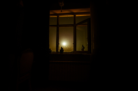 Night scene of moon seen through the window from dark room. Moonlight inside dark roomの写真素材