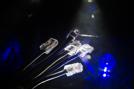 Network switch and ethernet cables, symbol of global communications. Colored network cables on dark background with lights and smoke. Selective focus. Network internet concept backgroundの写真素材