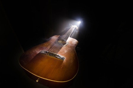 Music concept. Acoustic guitar isolated on a dark background under beam of light with smoke with copy space. Guitar Strings, close up. Selective focus. Fire effects. Surreal guitarの写真素材