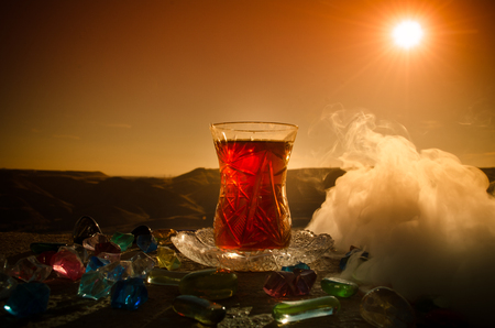 Turkish Azerbaijan tea in traditional glasse and pot outdoor nature background with sunlight and smoke. Eastern tea concept. Armudu traditional cup. Sunset timeの写真素材
