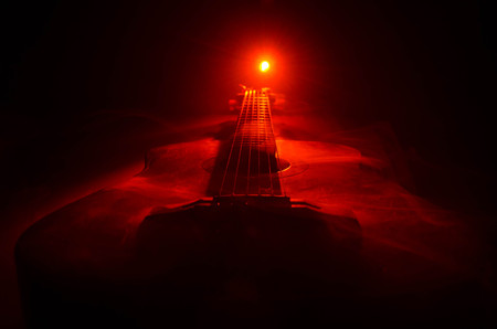 Music concept. Acoustic guitar isolated on a dark background under beam of light with smoke with copy space. Guitar Strings, close up. Selective focus. Fire effects. Surreal guitarの写真素材