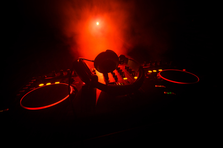 DJ Spinning, Mixing, and Scratching in a Night Club, Hands of dj tweak various track controls on dj's deck, strobe lights and fog, selective focus, close upの写真素材