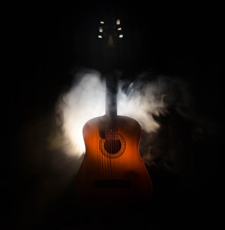 Music concept. Acoustic guitar isolated on a dark background under beam of light with smoke with copy space. Guitar Strings, close up. Selective focus. Fire effects. Surreal guitarの写真素材
