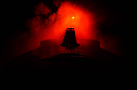 Music concept. Acoustic guitar isolated on a dark background under beam of light with smoke with copy space. Guitar Strings, close up. Selective focus. Fire effects. Surreal guitarの写真素材
