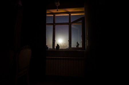 Night scene of moon seen through the window from dark room. Moonlight inside dark roomの写真素材