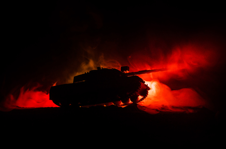 War Concept. Military silhouettes fighting scene on war fog sky background, German tank in action Below Cloudy Skyline At night. Attack scene. Armored vehicles. Tanks battle.の写真素材