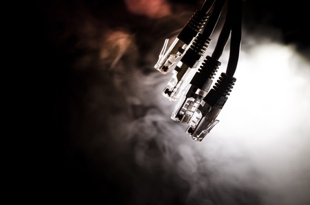 Network switch and ethernet cables, symbol of global communications. Colored network cables on dark background with lights and smoke. Selective focus. Network internet concept backgroundの写真素材