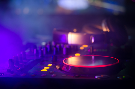 DJ Spinning, Mixing, and Scratching in a Night Club, Hands of dj tweak various track controls on dj's deck, strobe lights and fog, selective focus, close upの写真素材