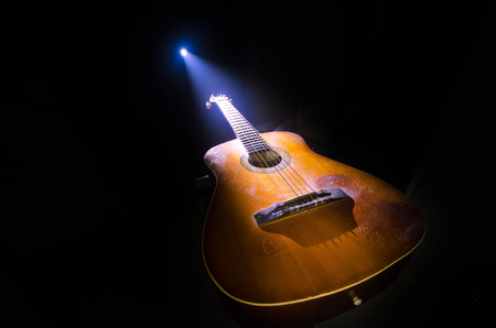 Music concept. Acoustic guitar isolated on a dark background under beam of light with smoke with copy space. Guitar Strings, close up. Selective focus. Fire effects. Surreal guitarの写真素材
