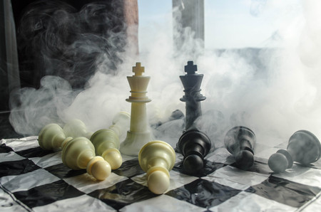 chess board game concept of business ideas and competition and strategy ideas concep. Chess figures on a dark background with smoke and fog and window with sunlight. Selective focusの写真素材
