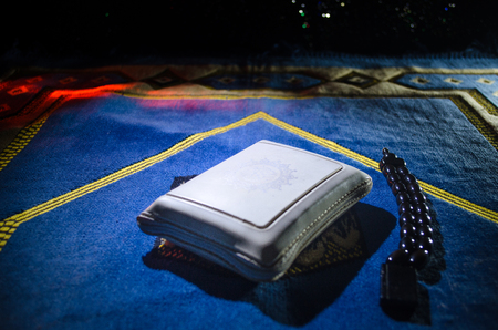 Holy Quran with beads on a prayer mat, Muslim Tasbih is a string of prayer beads which is traditionally used by Muslims along with the Quran. Ramadan holidays concept. Selective focusの写真素材