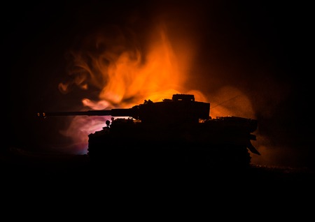 War Concept. Military silhouettes fighting scene on war fog sky background, German tank in action Below Cloudy Skyline At night. Attack scene. Armored vehicles. Tanks battle.の写真素材