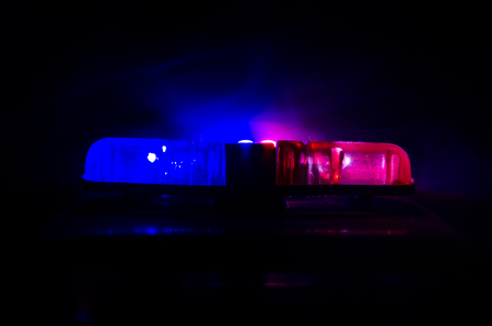 Red light flasher atop of a police car. City lights on the background.の写真素材