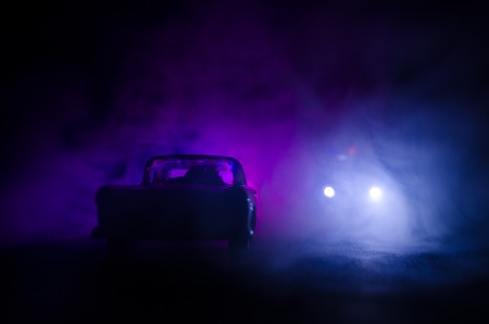 Police car chasing a car at night with fog background. 911 Emergency response police car speeding to scene of crime. Selective focusの写真素材
