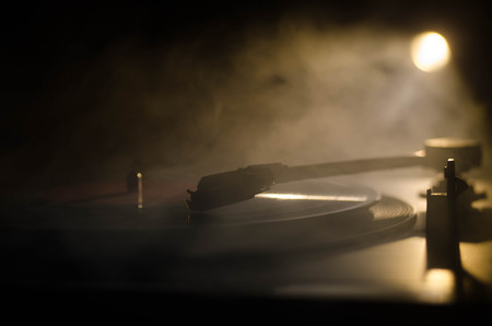 Turntable vinyl record player. Retro audio equipment for disc jockey. Sound technology for DJ to mix & play music. Vinyl record being played against burning fire background with smokeの写真素材