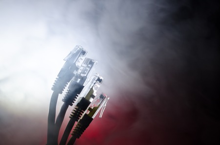 Network switch and ethernet cables, symbol of global communications. Colored network cables on dark background with lights and smoke. Selective focus. Network internet concept backgroundの写真素材