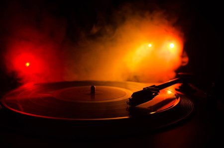 Turntable vinyl record player. Retro audio equipment for disc jockey. Sound technology for DJ to mix & play music. Vinyl record being played against burning fire background with smokeの写真素材
